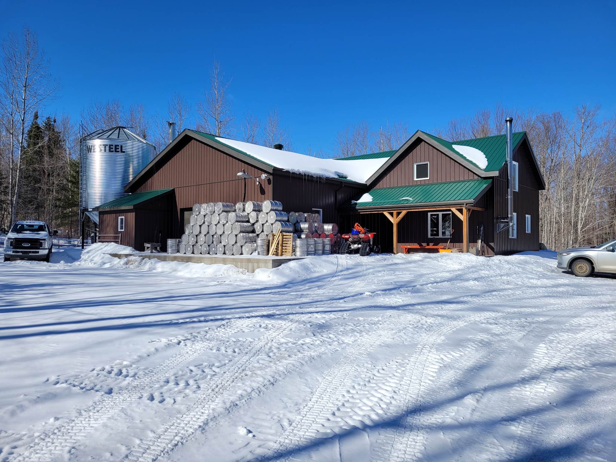 Canadian Maple Syrup Facility in Winter with Stacked Barrels and Snowy Landscape